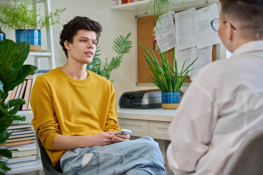 Teen meeting with an ADHD coach in a bright office, discussing time management and focus strategies for ADHD support.