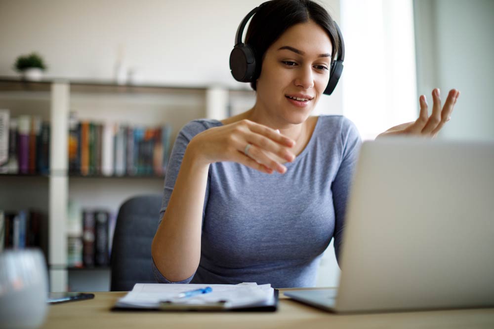 Woman in headphones talking with an ADHD coach during an online session, discussing structured goal-setting and productivity strategies.
