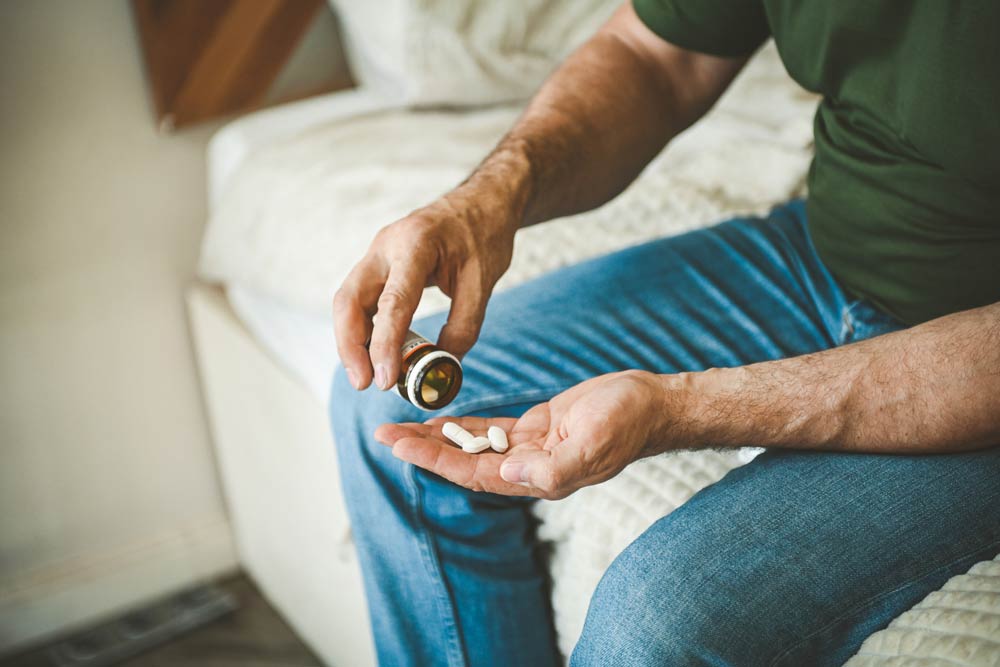 Close-up of a man’s hands pouring ADHD medication pills into his palm during dosage adjustment.