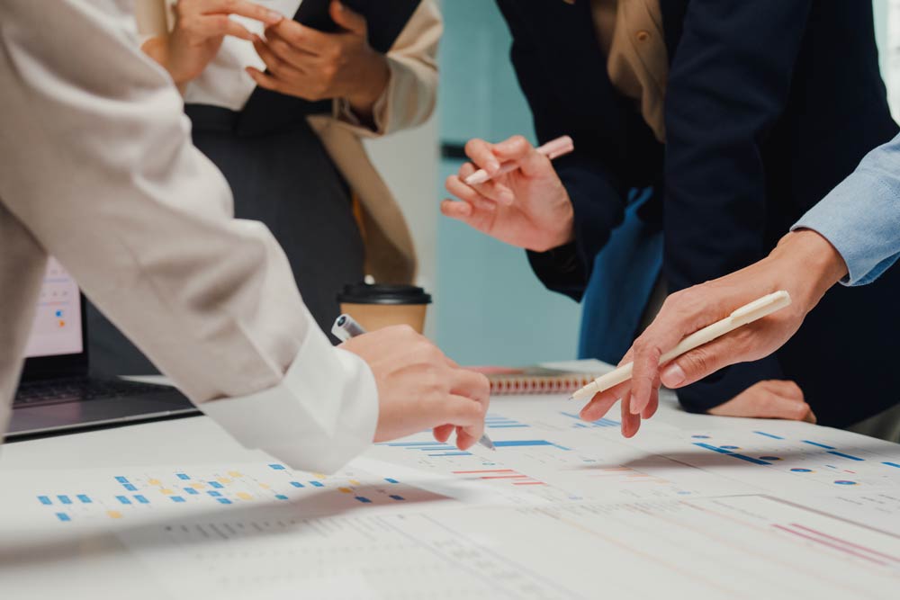 Close-up of professionals collaborating around a table reviewing career plans and documents, symbolizing teamwork and strategic planning for adults with ADHD managing career transitions.