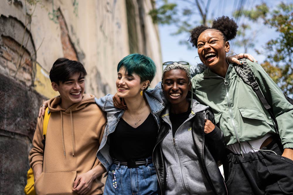 Diverse group of young adults laughing together outdoors, symbolizing friendships and support networks for ADHD students.