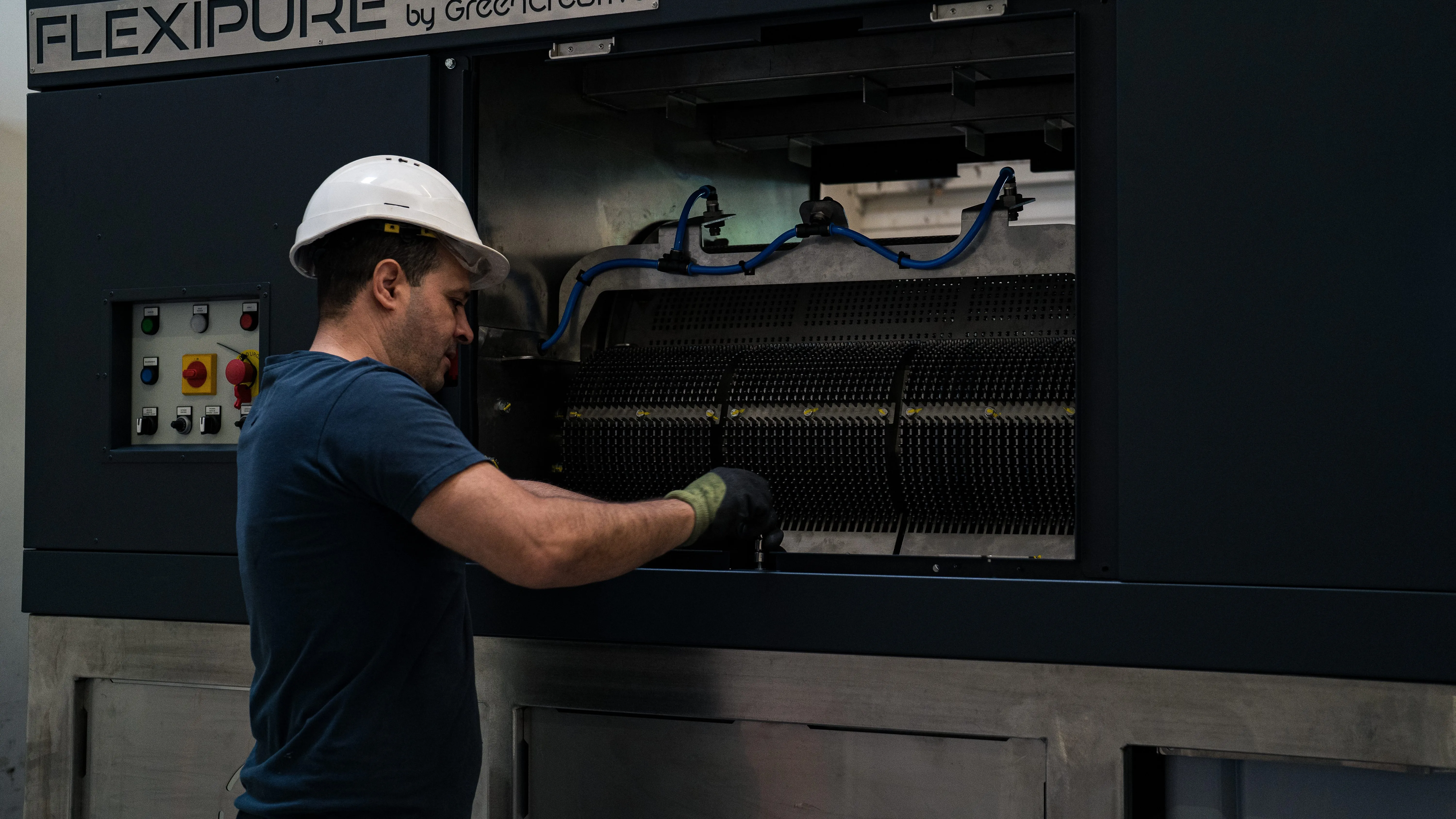 Man in a white safety helmet operating industrial machinery labeled FLEXIPURE.