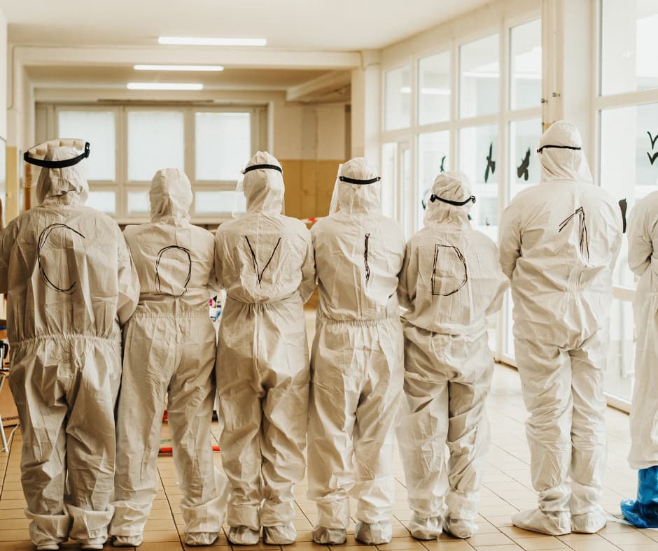 Menschen in Schutzanzügen während der Corona-Pandemie – Symbolbild für Unsicherheit, Entscheidungen unter unvollständigen Informationen und den Rückschaufehler.