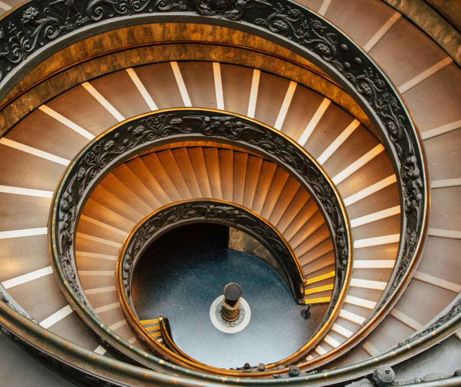 Spiralförmige Treppe von oben fotografiert als Symbol für eine mentale Negativspirale, Gedankenkarussell und den Weg aus belastenden Denkmustern.
