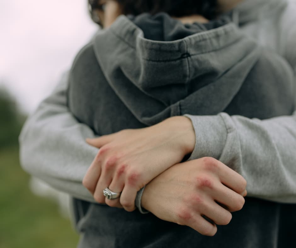 Person umarmt sich selbst als Symbol für Verlustangst, emotionale Abhängigkeit und Klammern in Beziehungen.