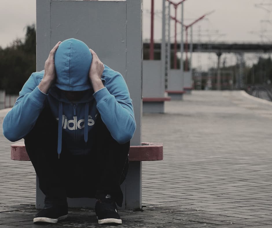 Mann in blauem Kapuzenpullover sitzt zusammengesunken auf dem Boden – Symbol für Angst, Überforderung und innere Blockade.