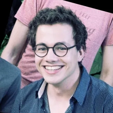 Smiling young man with glasses in a casual setting, representing teamwork in data science and machine learning projects.