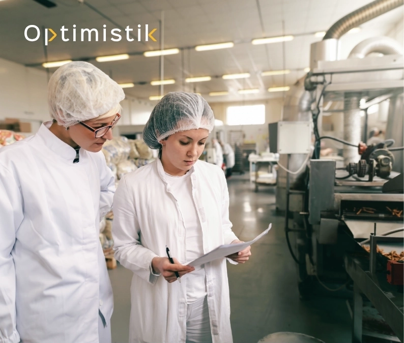 Deux ingénieurs en blouse blanche analysant des données de production dans une usine agroalimentaire