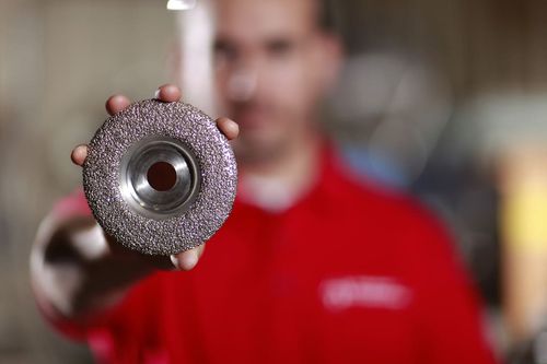 Abrasive Technology employee holding a grinding wheel to the camera