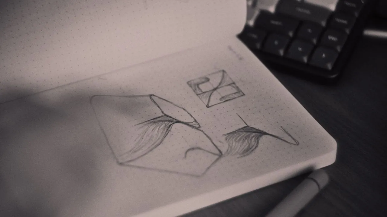Photo of a sketchbook with a blurry hand sketching a design