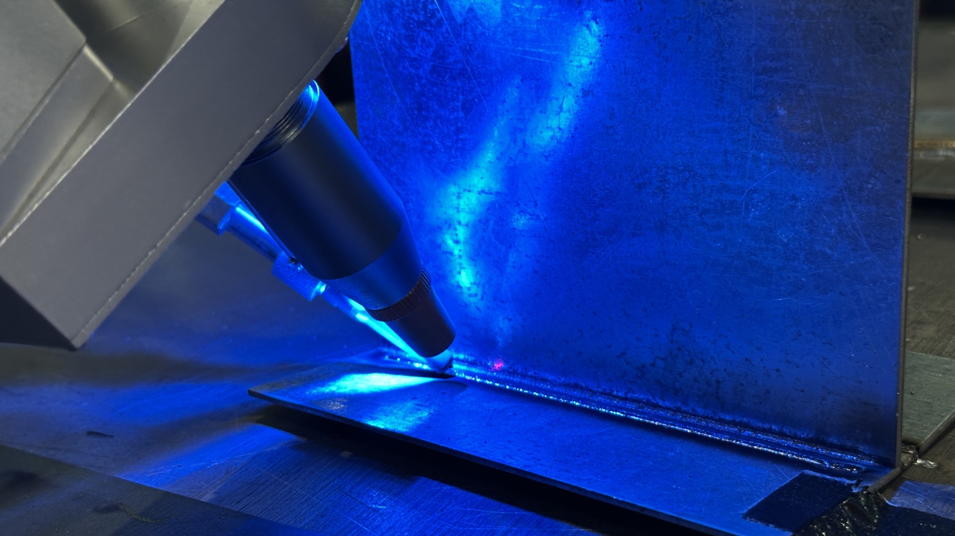 Máquina de solda a laser sendo utilizada para soldar duas placas de metal.