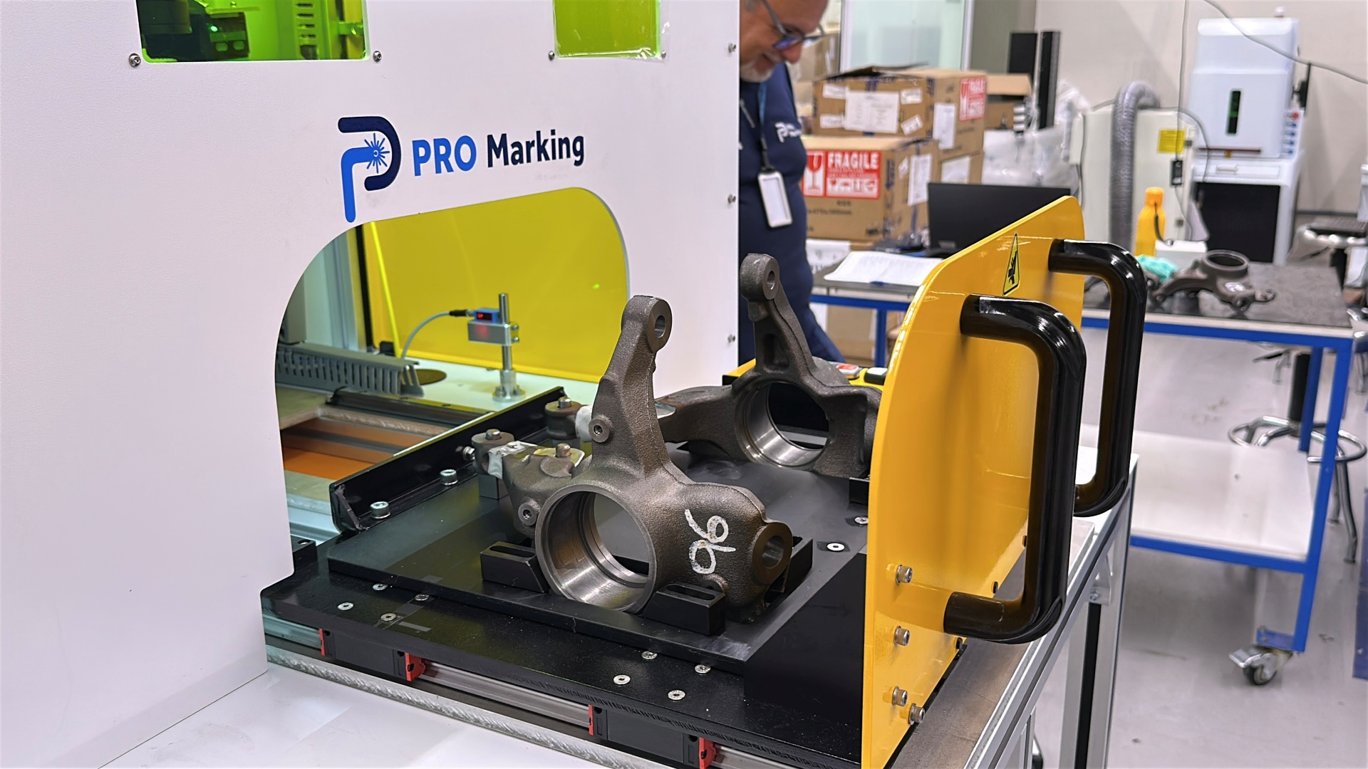 Peças automotivas de metal sendo preparadas para gravação a laser.