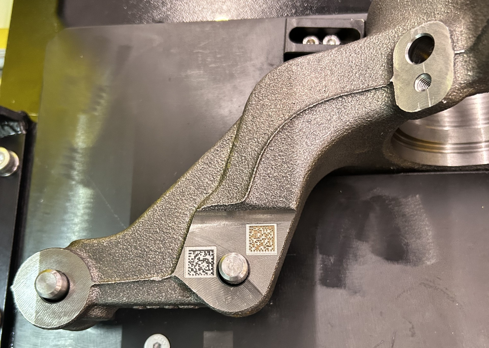 Testes de gravação a laser de códigos data matrix realizados em peça automotiva de metal.