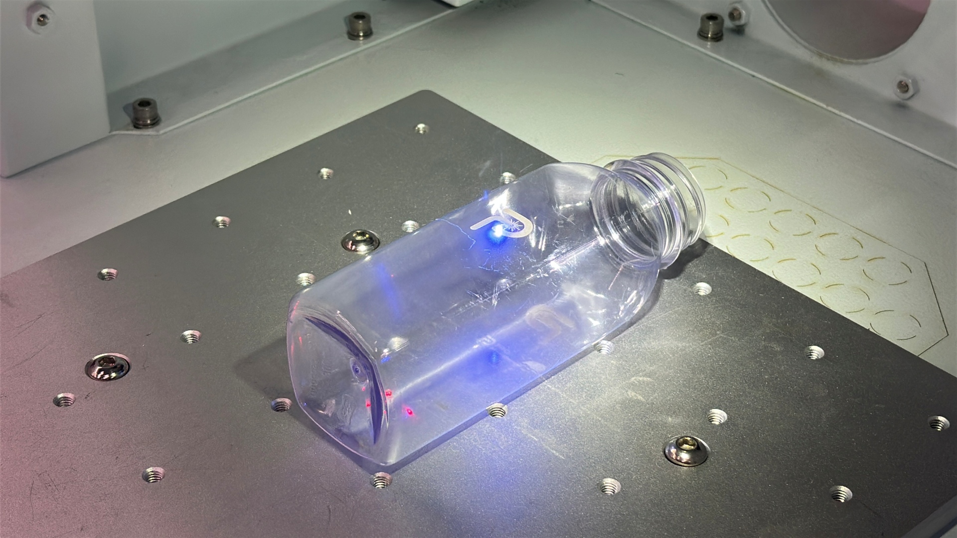 Gravação a laser sendo feita em garrafa de plástico.