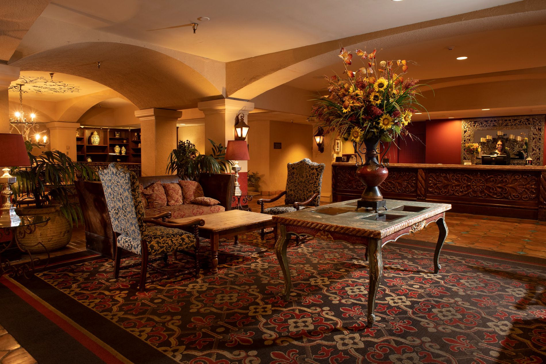 Lobby of Hotel Encanto with seating area, vase with sunflowers and view of the front desk