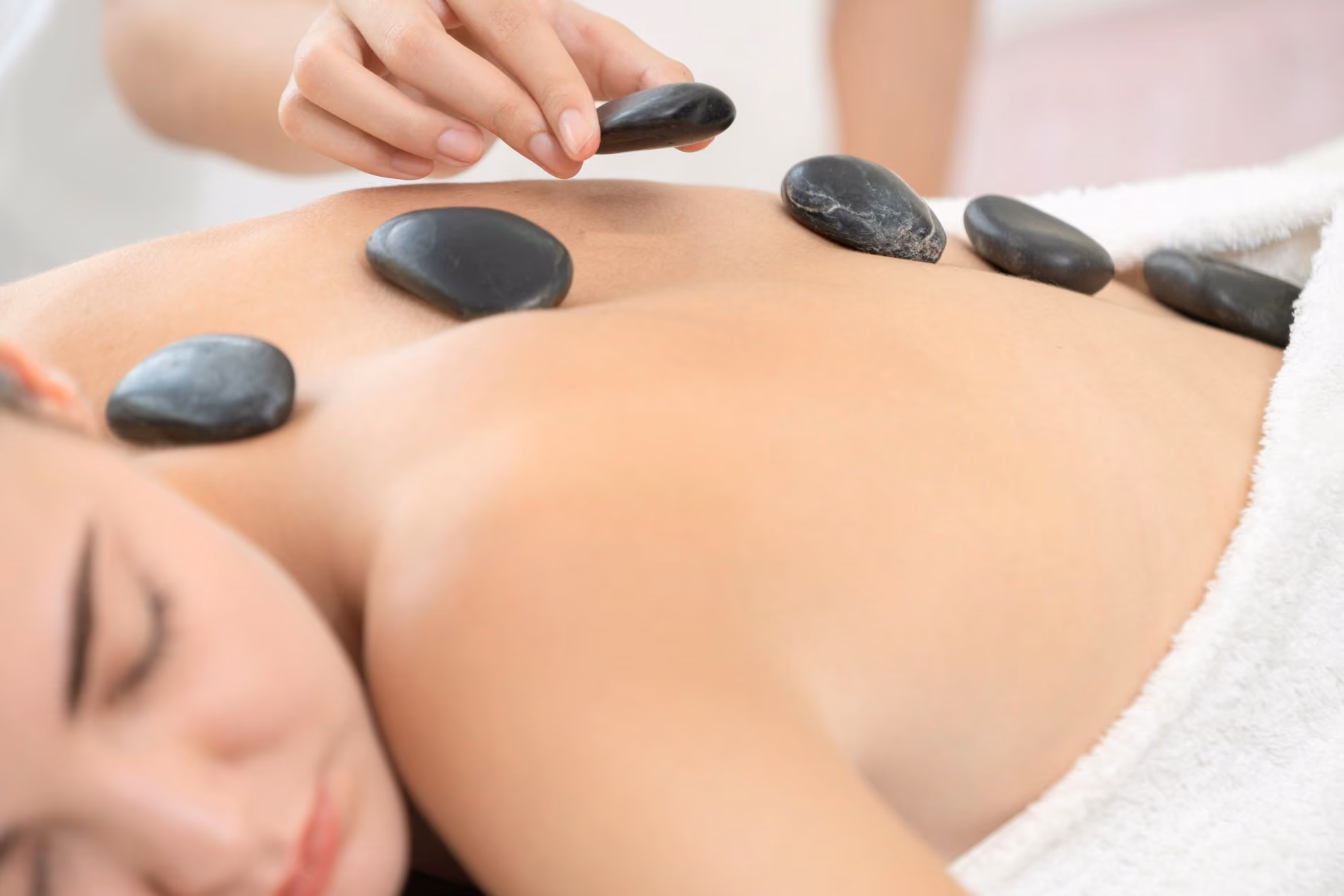 Woman with black stones being laid on back in a spa