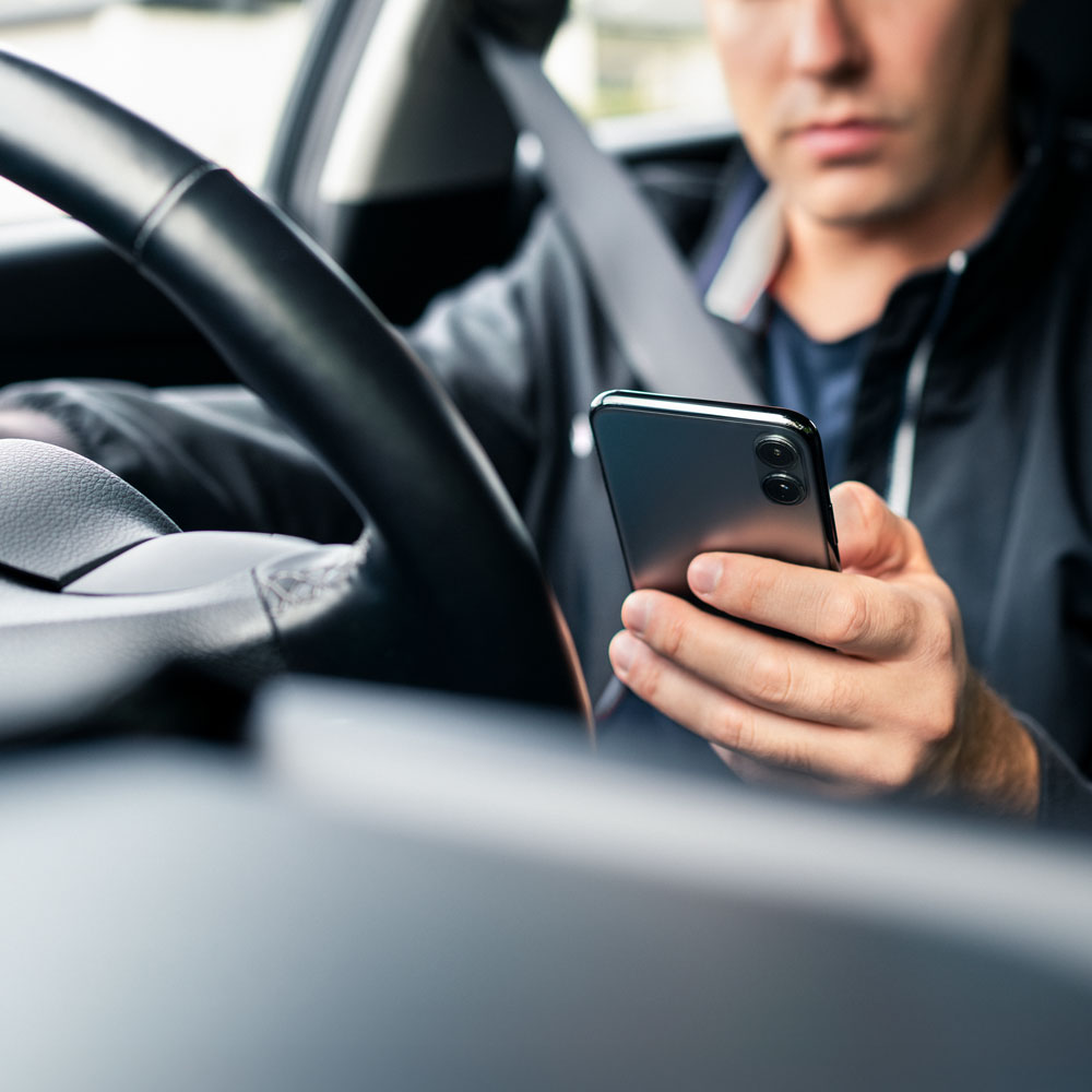 Person using mobile phone while driving.