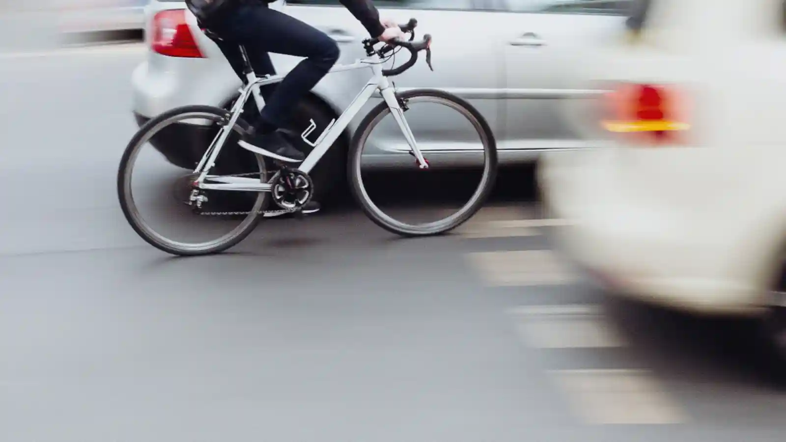 Commuter cyclist in traffic between two cars