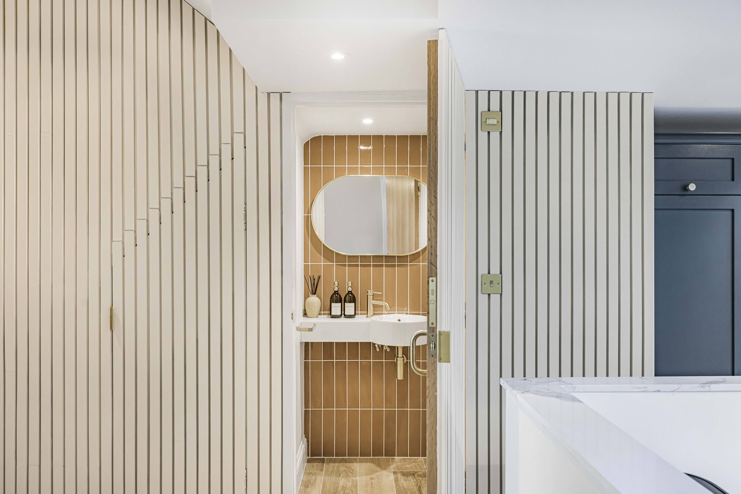 Slatted panelling and the cloakroom with an oval mirror and basin at Ravensbury Terrace