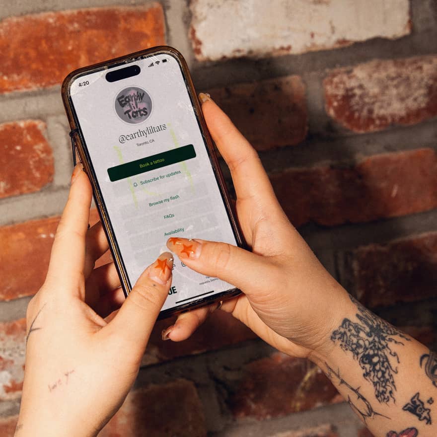 Hands holding a phone browsing an artist's website on Venue Ink