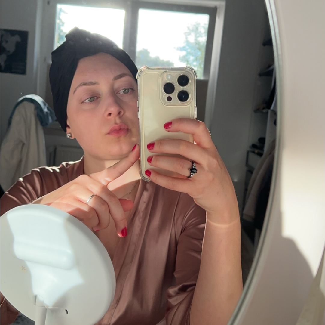 Eine junge Frau mit Turban fotografiert sich im Spiegel.