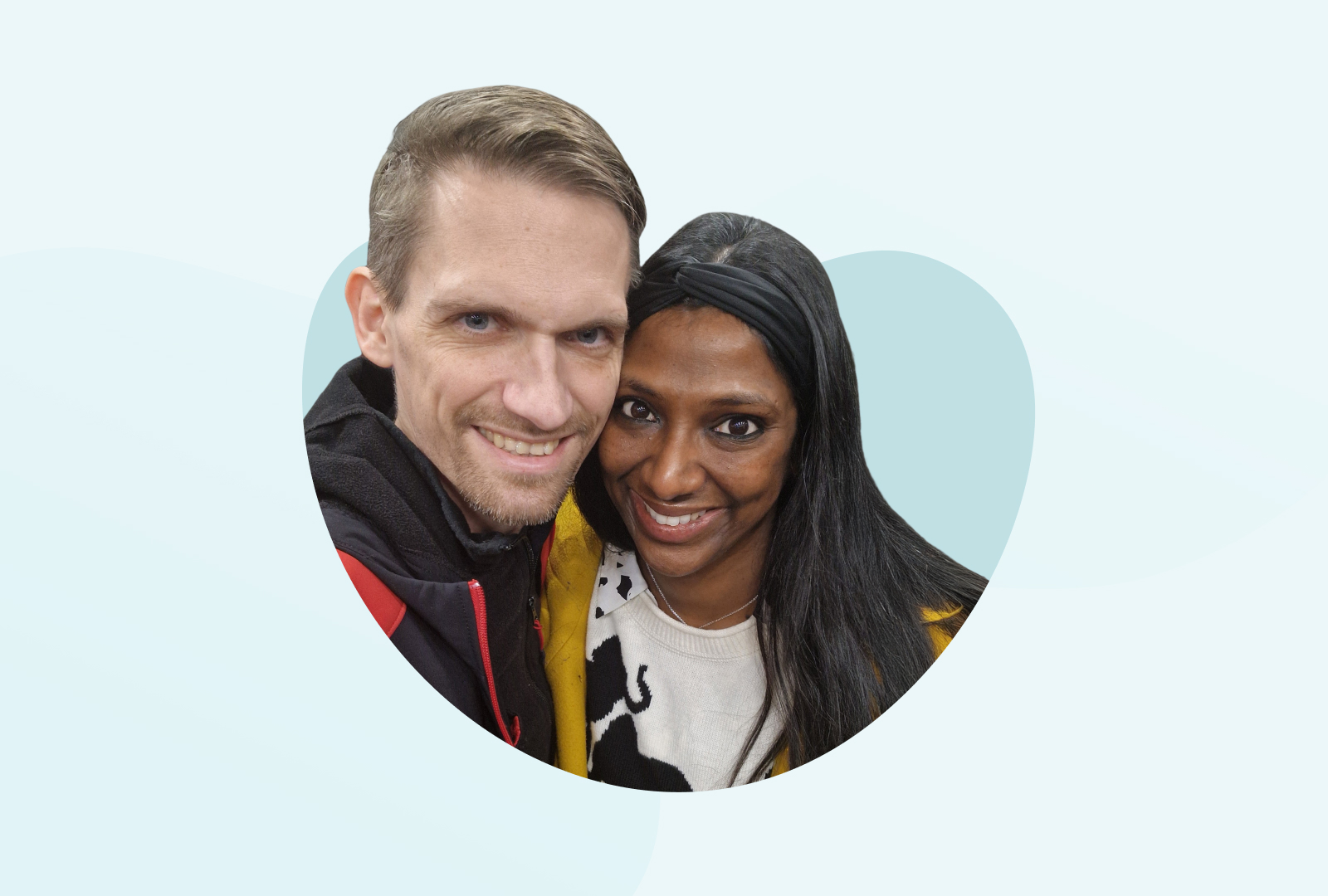 Freddy, links im Bild und Nadine, rechts im Bild, lächeln, die Köpfe dicht beieinander, in die Kamera.