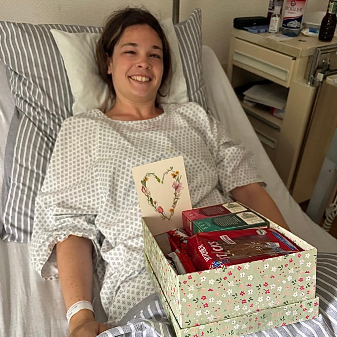 Alina liegt im Krankenhaus und eine Geschenk-Box vor sich.
