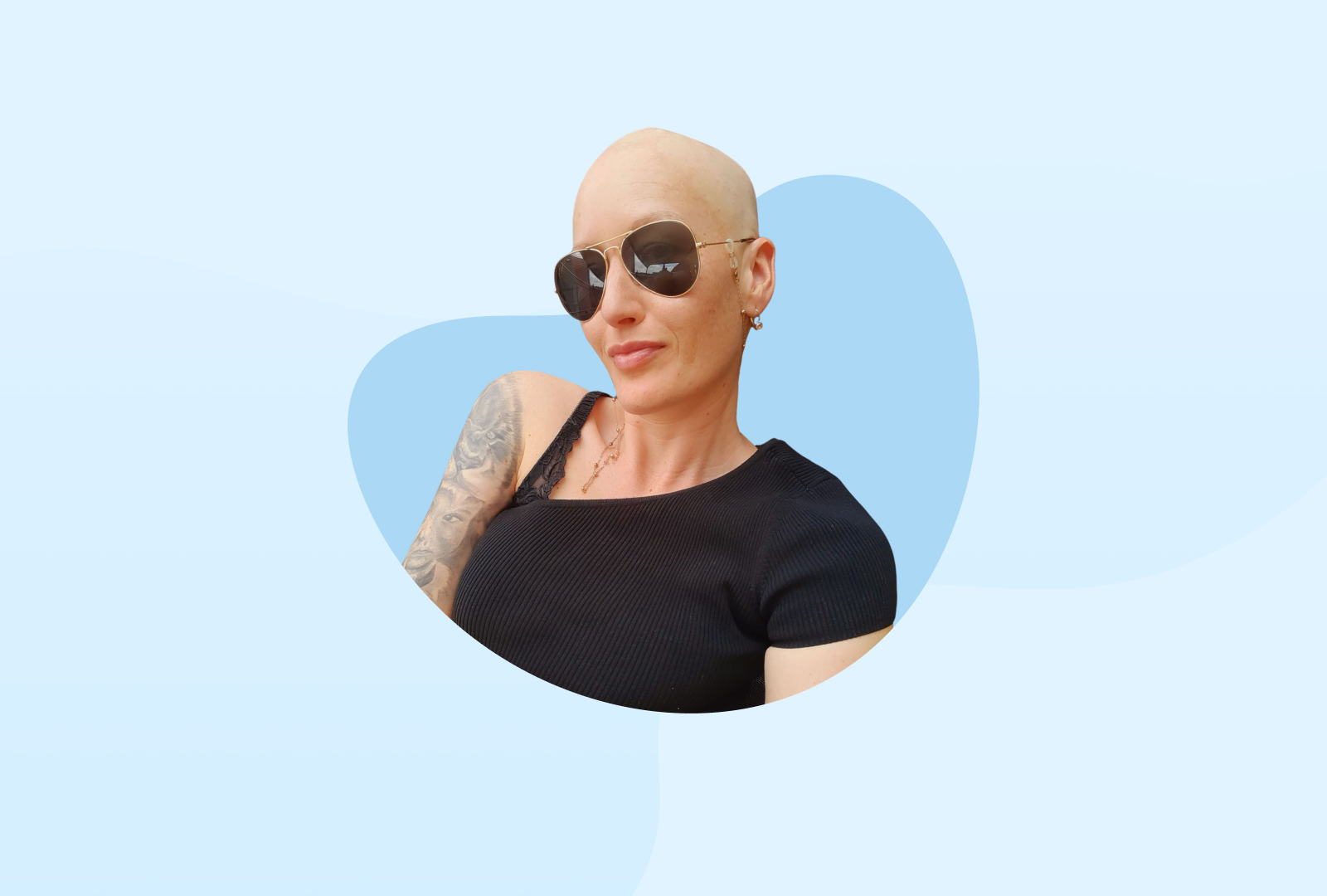 Lisa trägt eine Sonnebrille und ein schulterfreier Oberteil, welches ihr Tattoo zeigt.