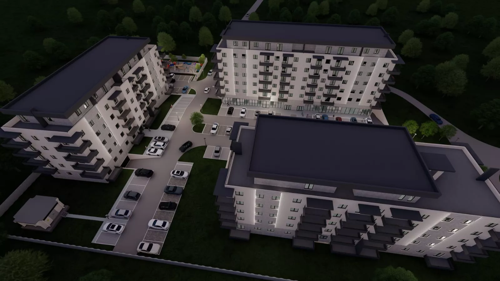 Aerial night view of a residential complex with three modern multi-story apartment buildings, outdoor parking, and surrounding greenery.