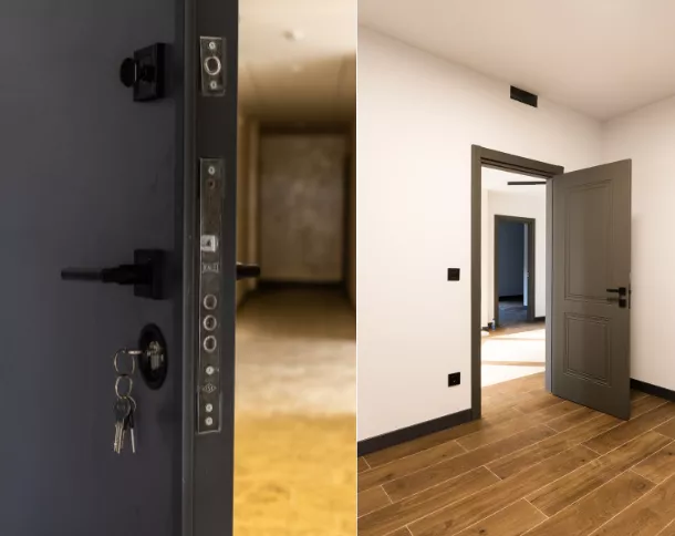 Open dark gray door with keys in the lock leading to a bright room with wooden floor and white walls.