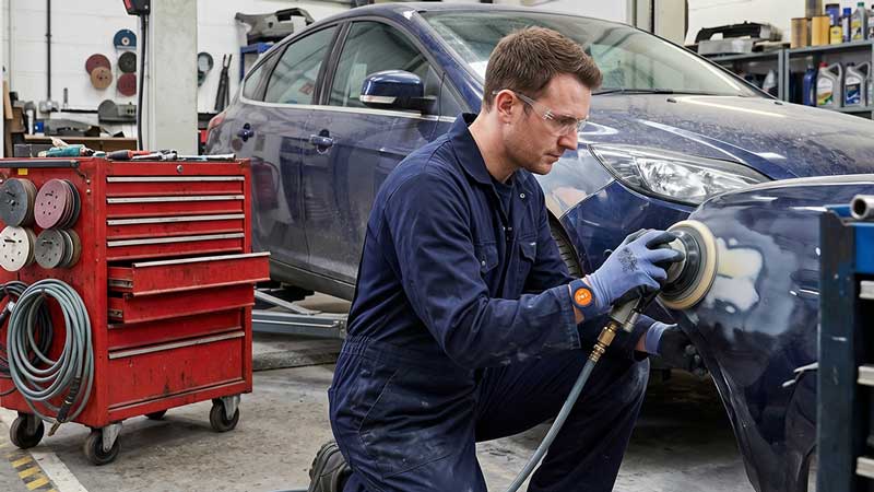 man using sander in car bodyshop accumulating hand arm vibrationb