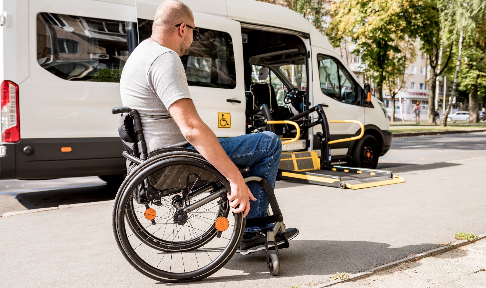Rollstuhlfahrer vor einem behindertengerechten Fahrzeug mit Rollstuhllift