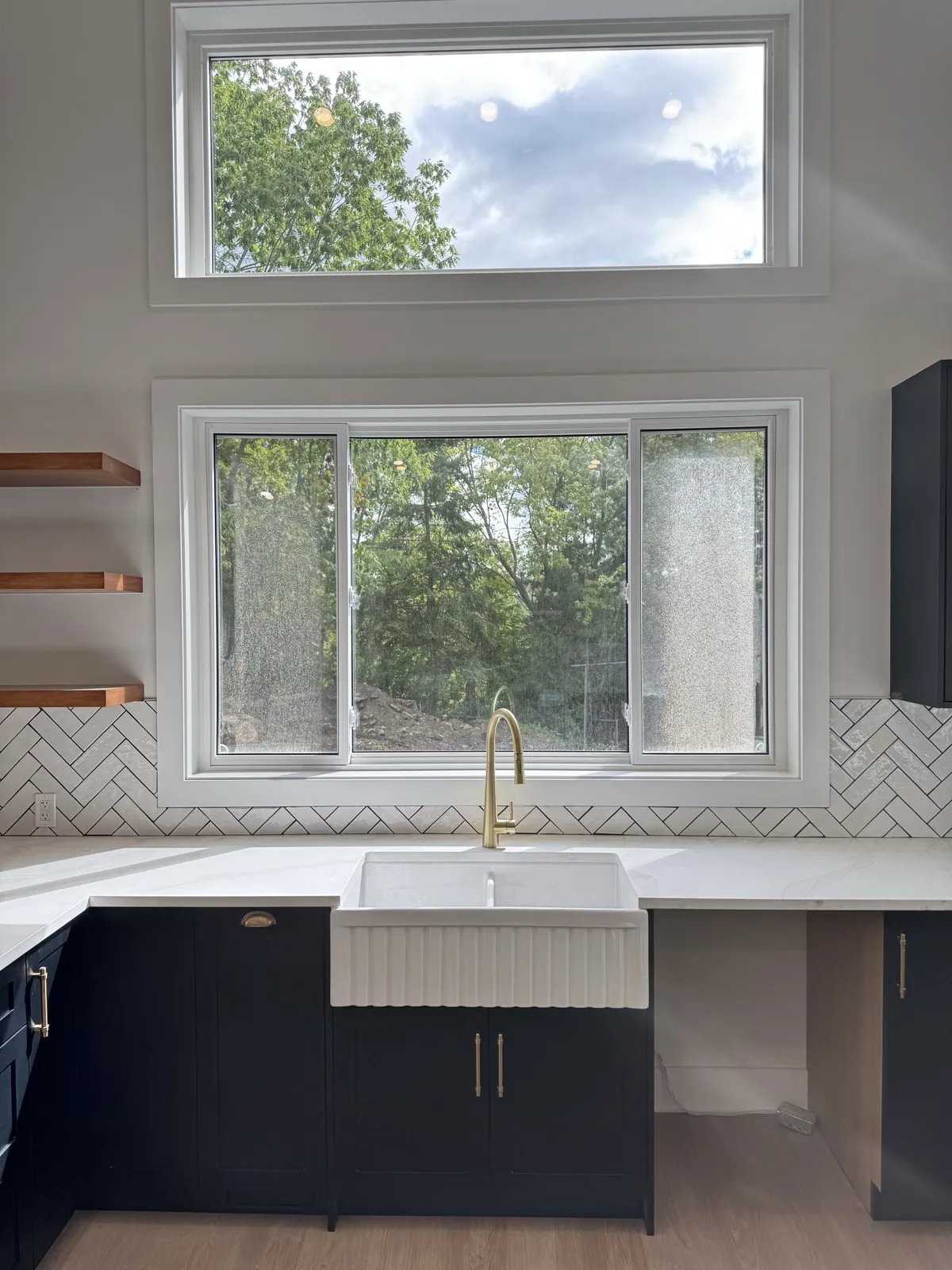 Farmhouse sink under a tall window and clerestory in the addition kitchen