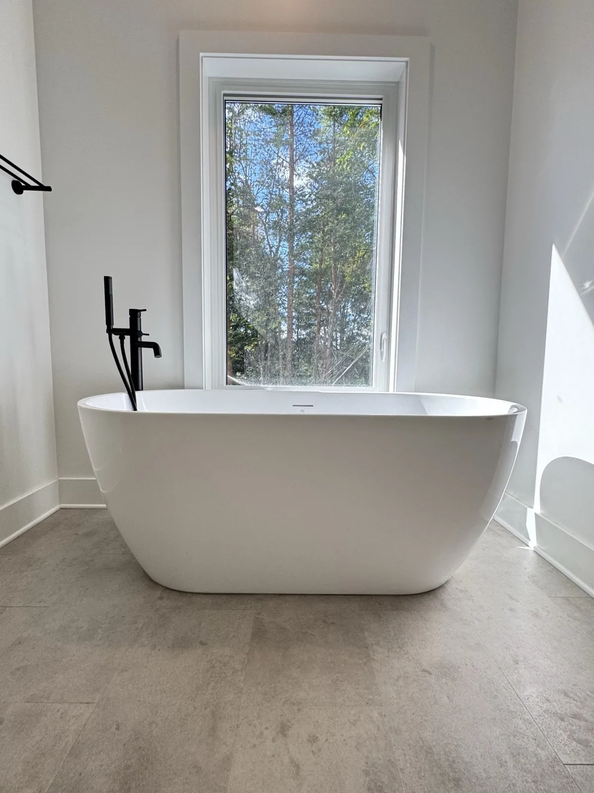 Freestanding soaker tub under a tall window in the addition's primary ensuite