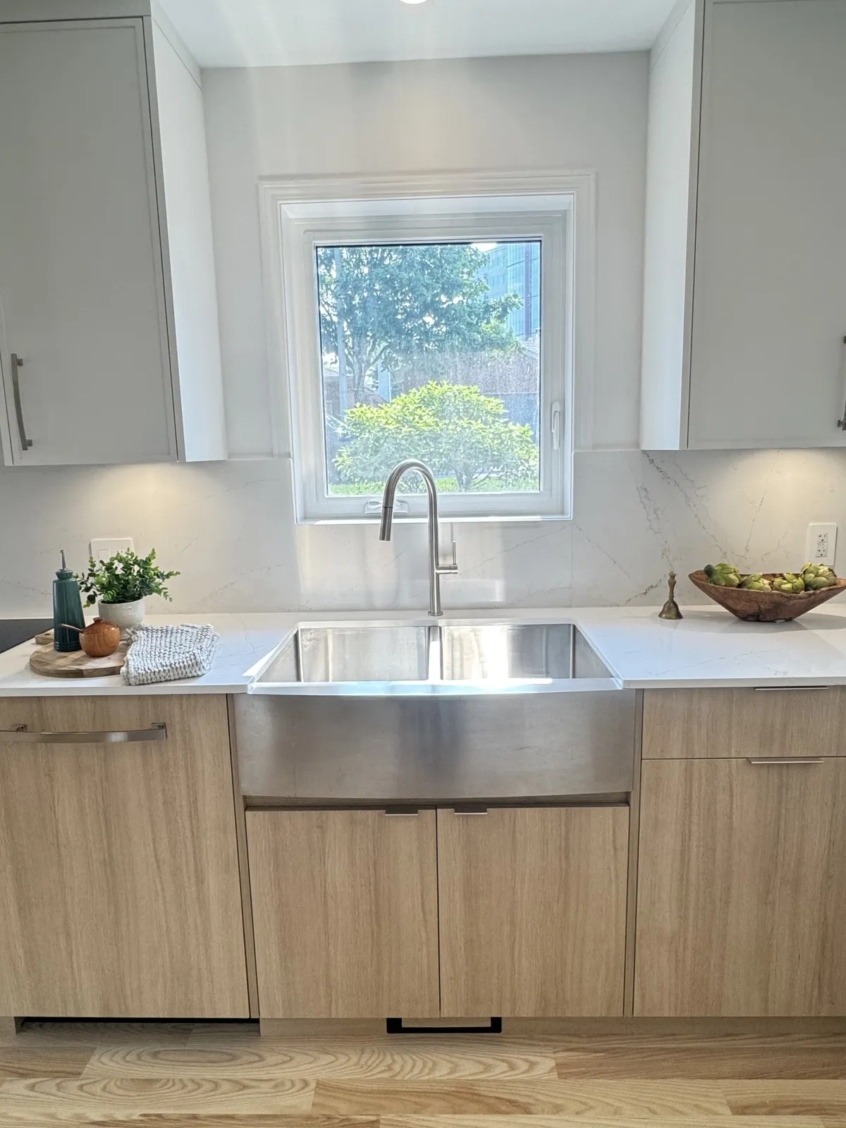 Stainless apron sink with quartz slab backsplash under the kitchen window