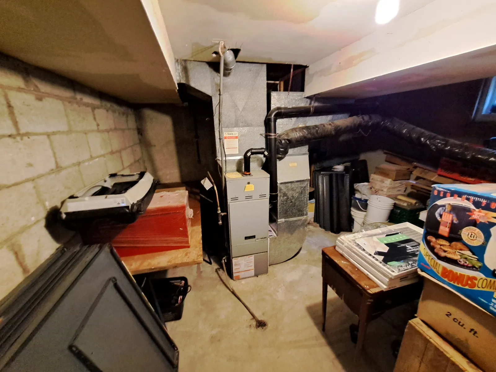 Old furnace and ductwork against a concrete block wall