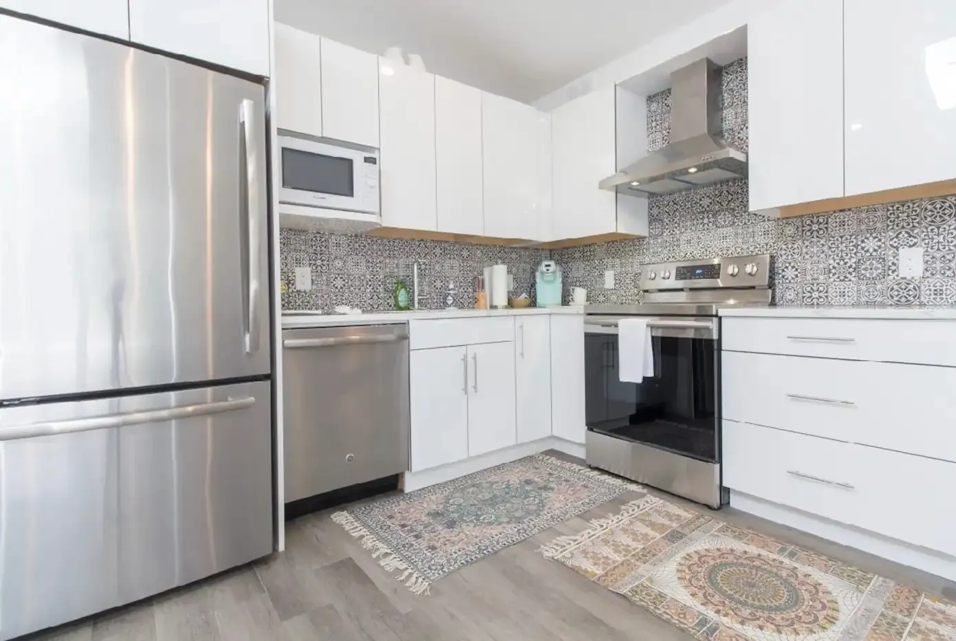 Coach house kitchen with stainless appliances, range hood and patterned tile backsplash