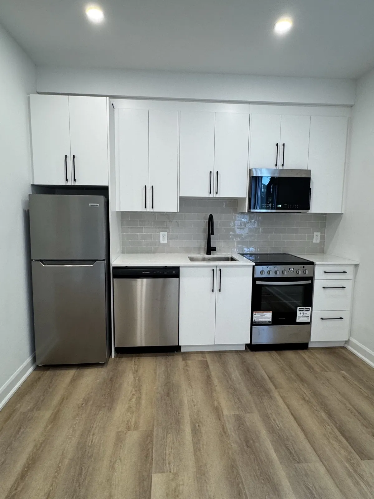 Unit kitchen with white flat-panel cabinets, subway tile backsplash and stainless appliances