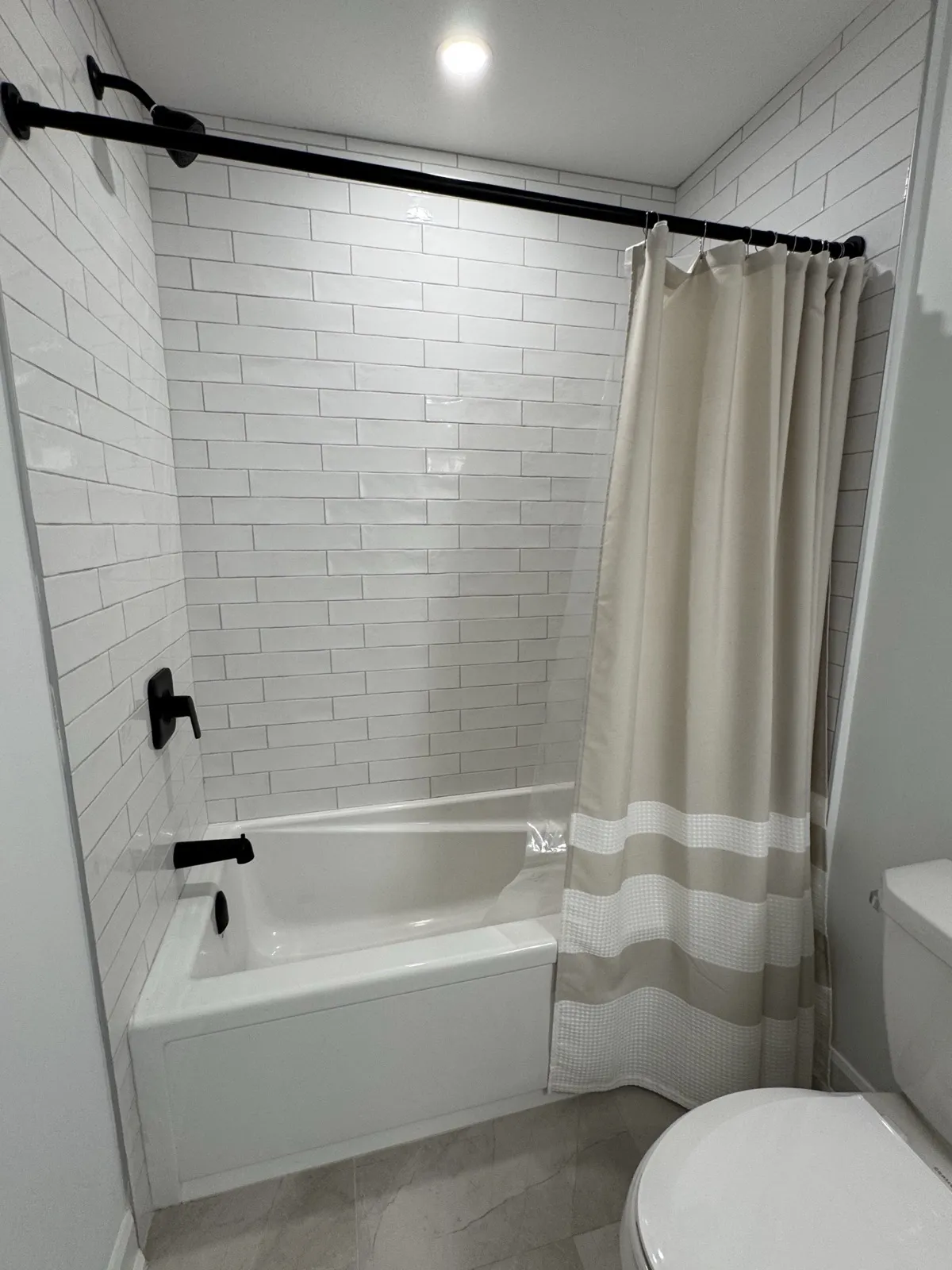 Tub with a white subway tile surround and black fixtures