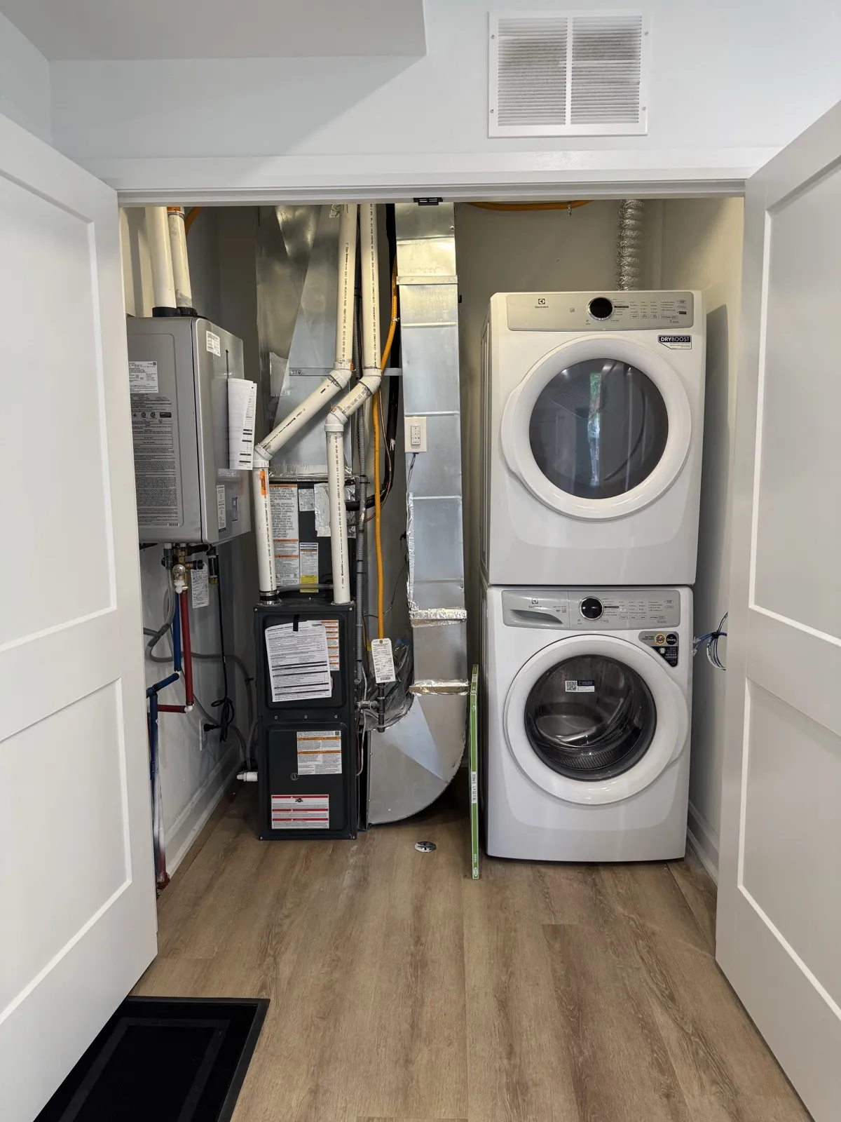 In-suite mechanical closet with a furnace, tankless water heater and stacked washer and dryer