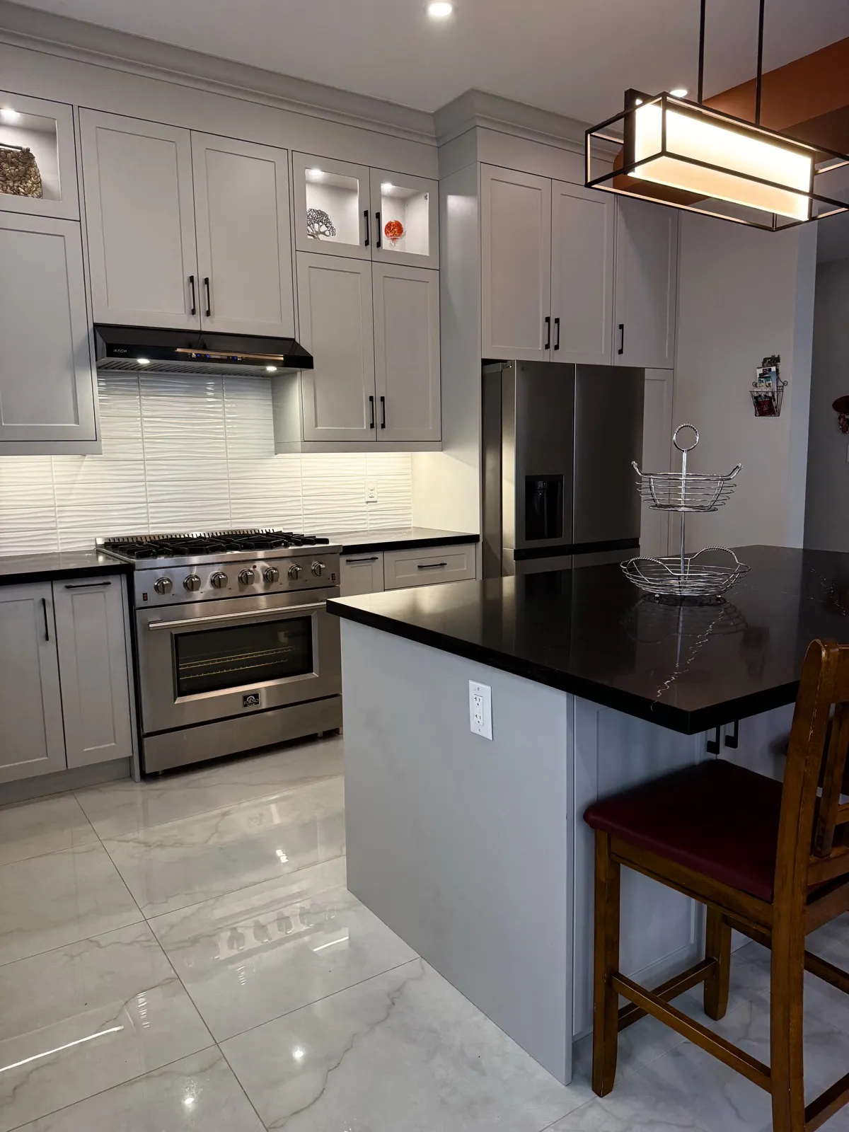 Six-burner gas range, textured white backsplash and island with black quartz counter