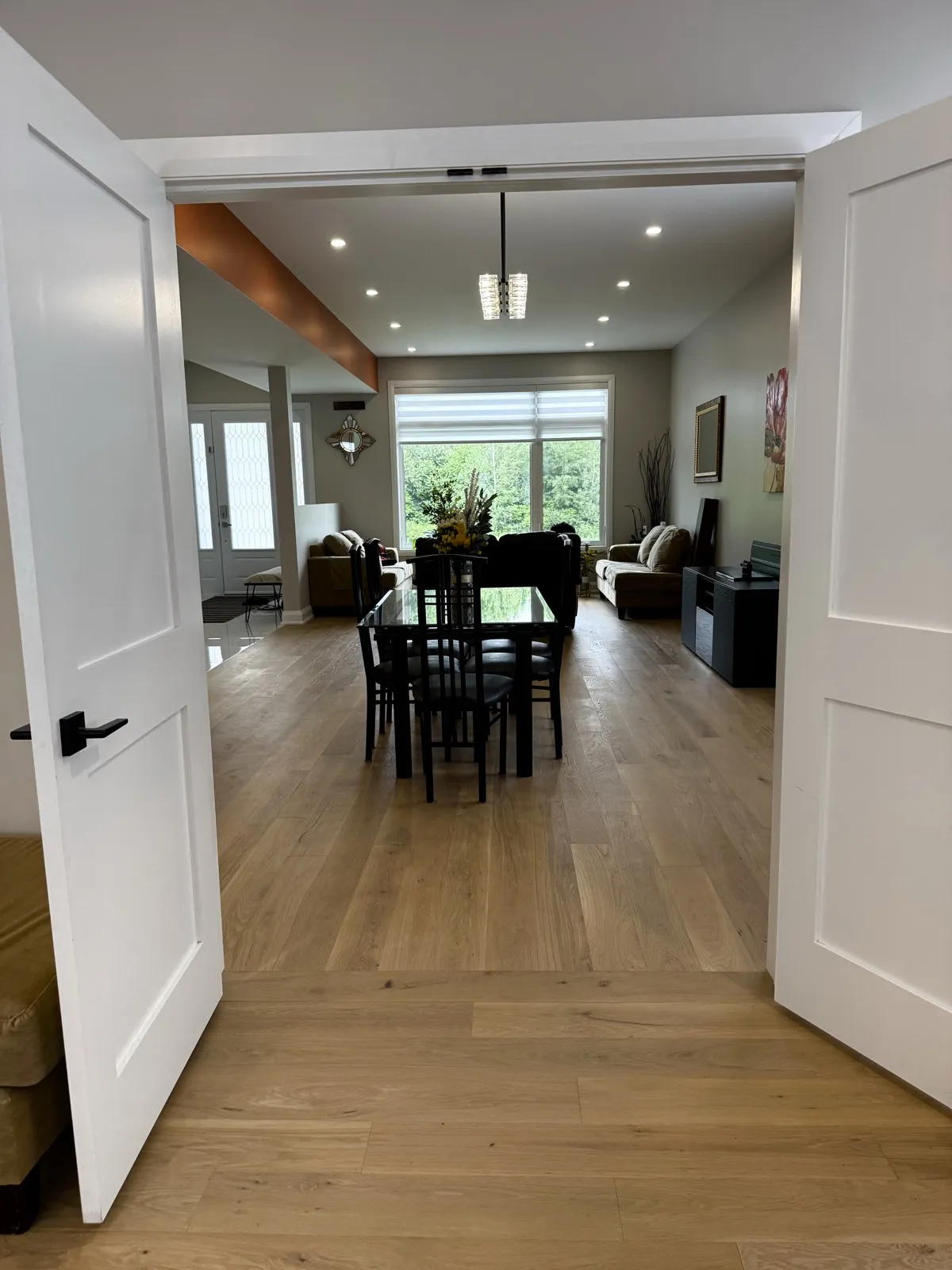 View through double doors to the open dining and family room with oak floors