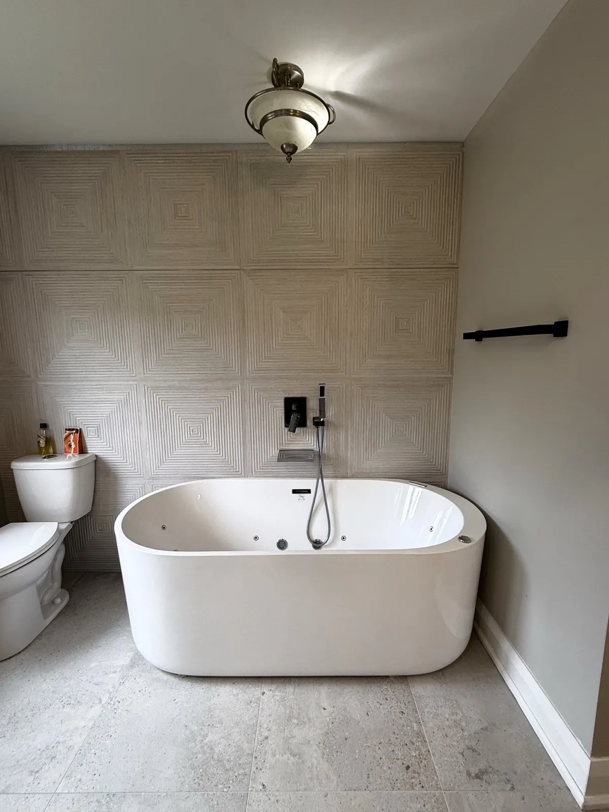 Primary ensuite with a freestanding jetted tub against a textured feature wall