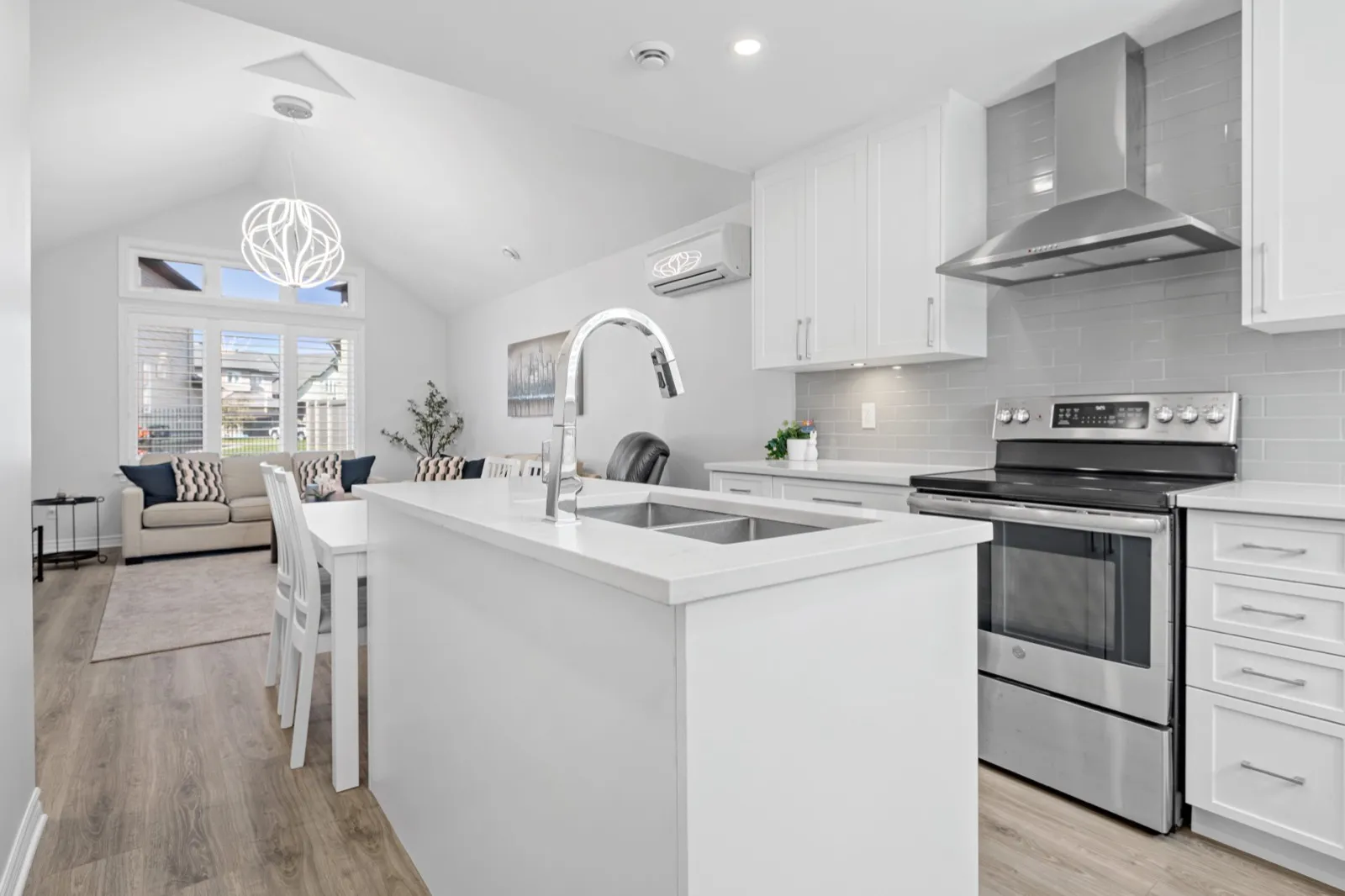Coach house kitchen island with a double sink looking into the vaulted living room