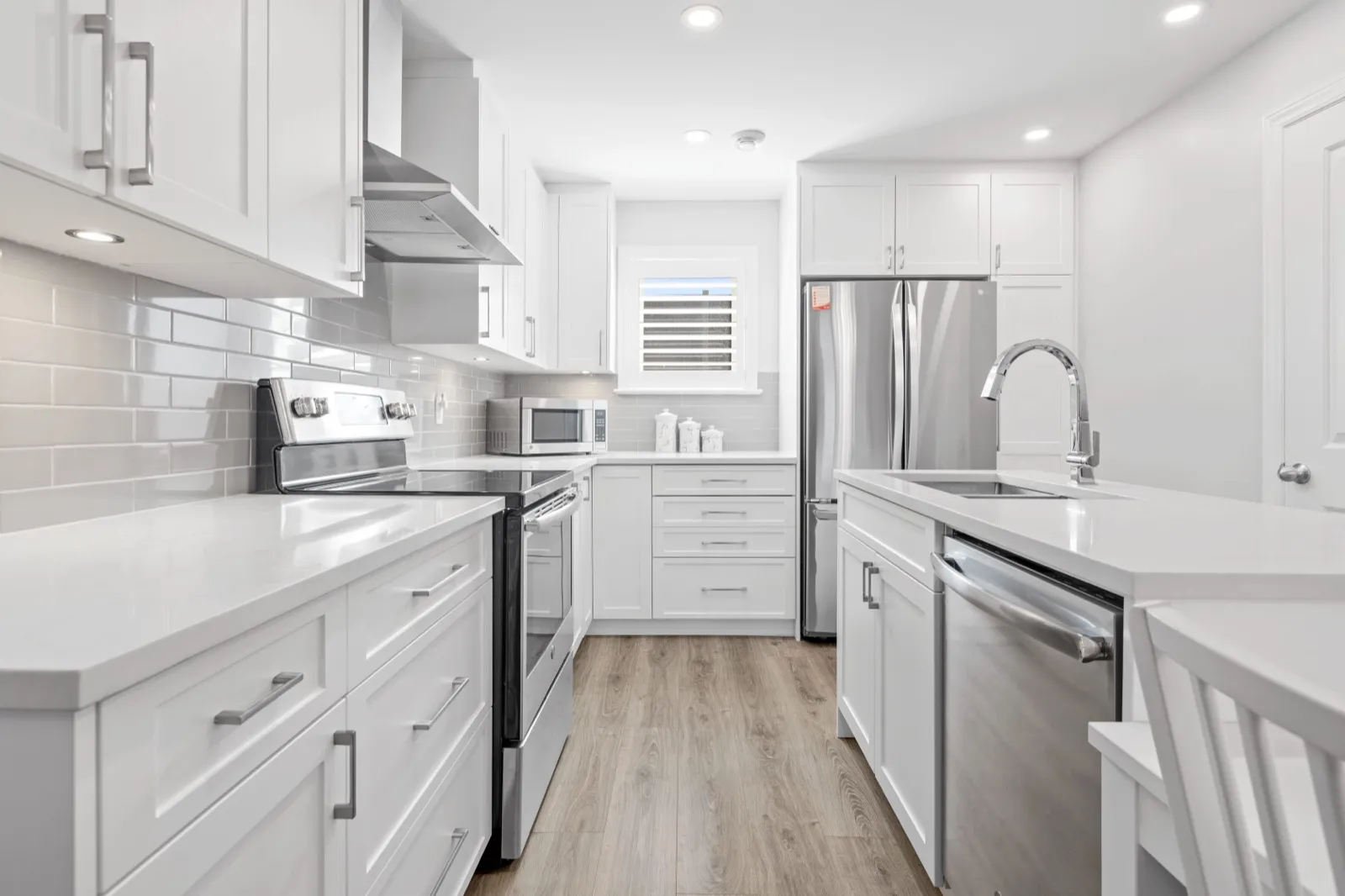 White Shaker kitchen with quartz counters, subway tile and stainless appliances