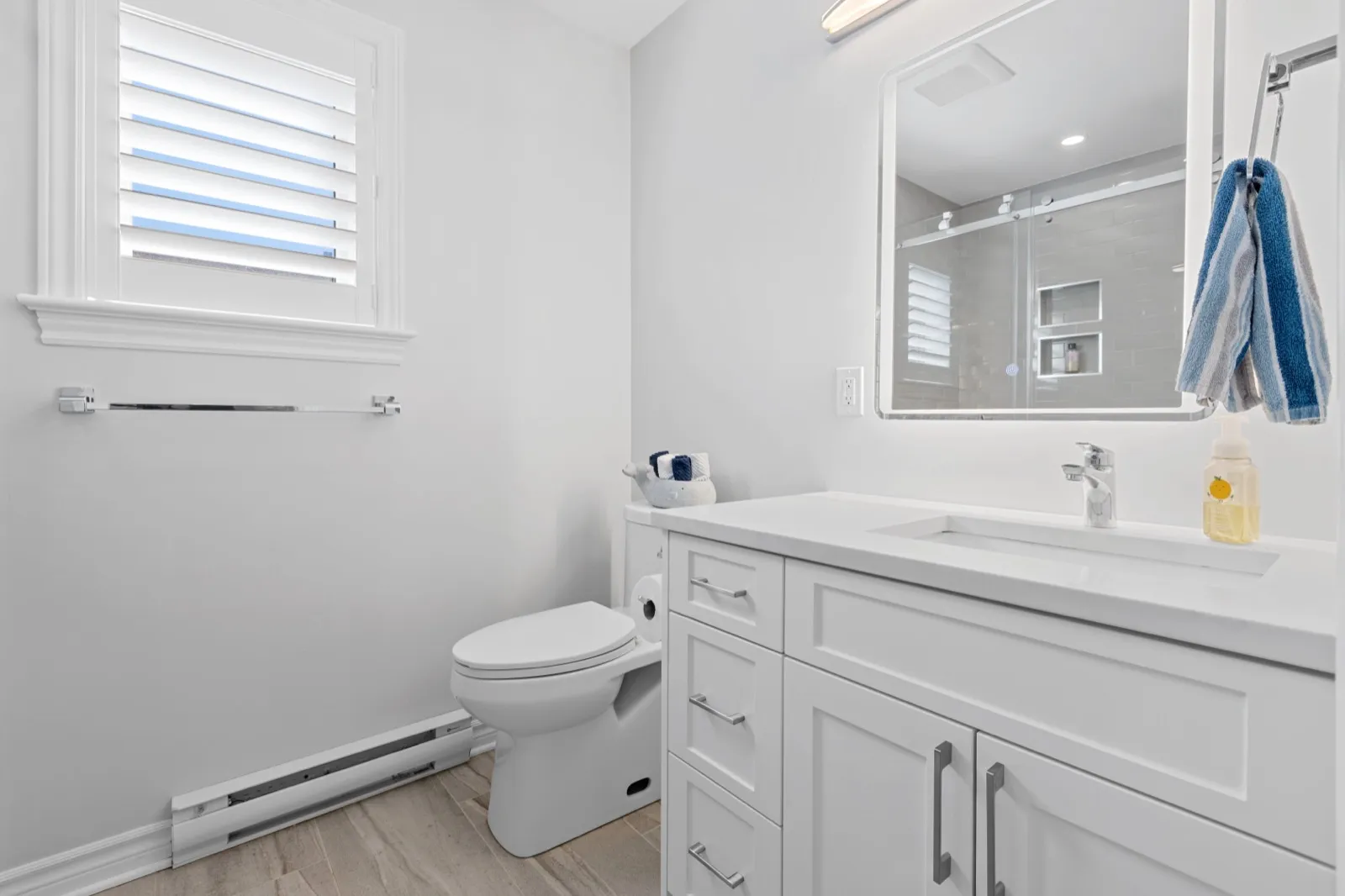 Coach house bathroom with a Shaker vanity, backlit mirror and glass shower