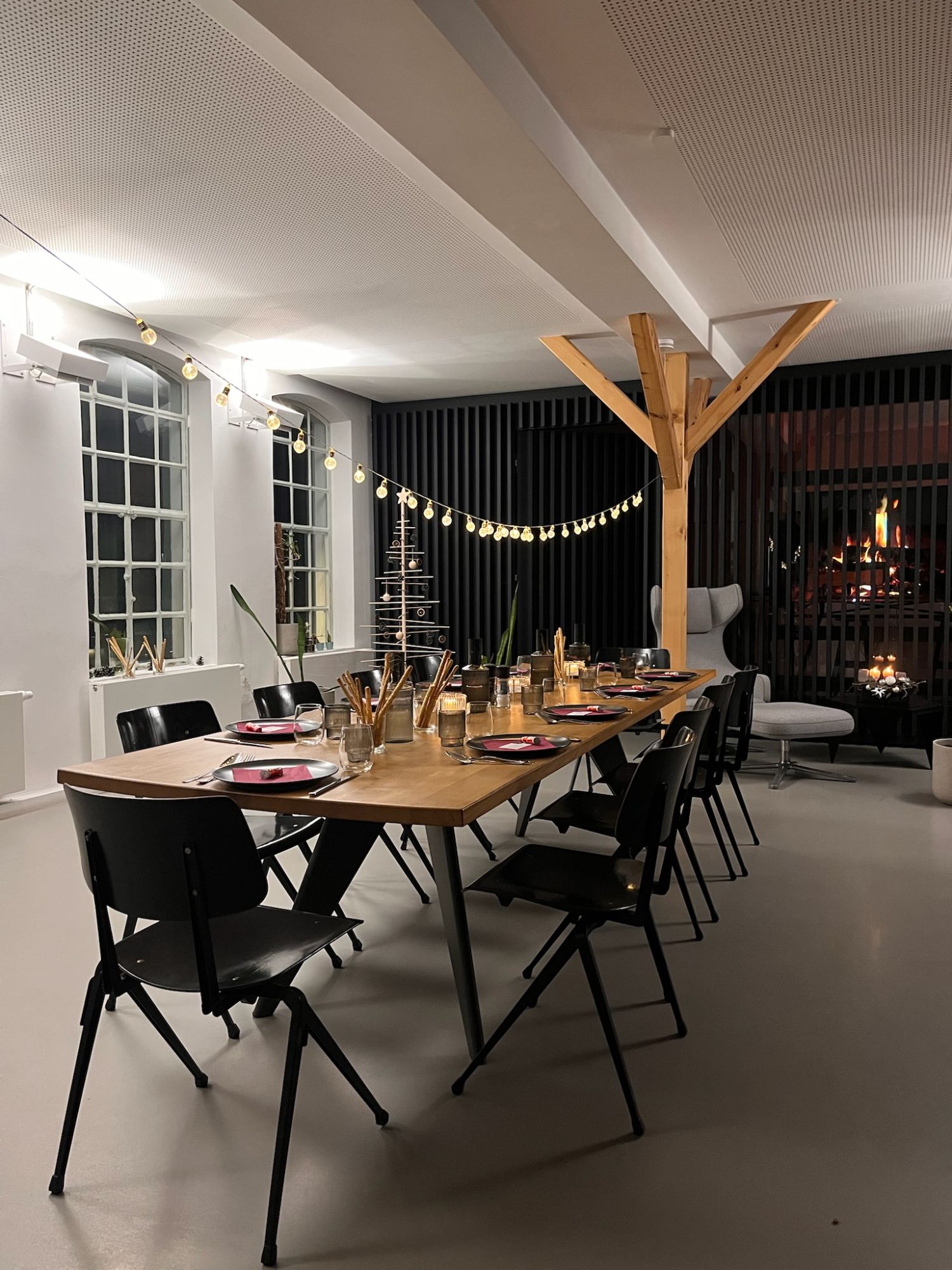 Der lange Holztisch im Rainhaus, gedeckt mit Tellern, Gläsern und Kerzen, daneben schwarze Stühle