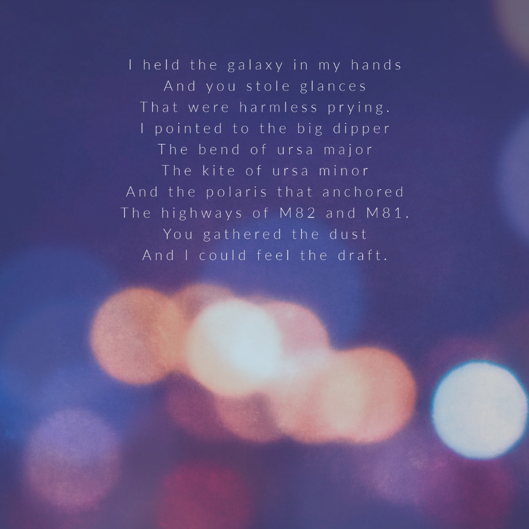 A graphic designed image of orange, pink and blue bokeh dots on a purple background, resembling lights at night. There are lines of poetry starting from the top-centre of the image: "I held the galaxy in my hands/ And you stole glances/ That were harmless prying./ I pointed to the big dipper/ The bend of ursa major/ The kite of ursa minor/ And the polaris that anchored/ The highways of M82 and M81./ You gathered the dust/ And I could feel the draft."