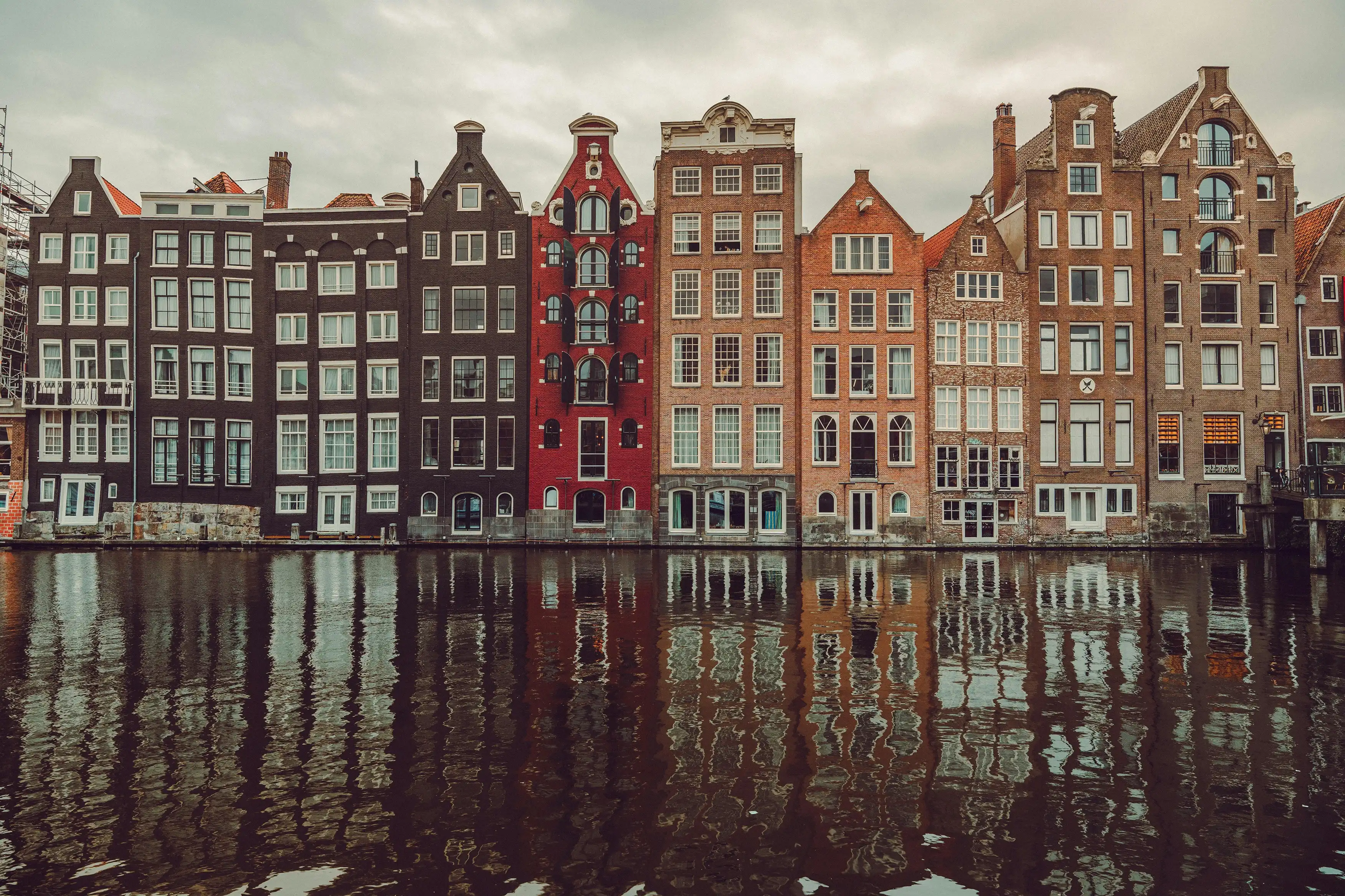 A row of traditional gabled canal houses reflected in an Amsterdam canal, the Netherlands