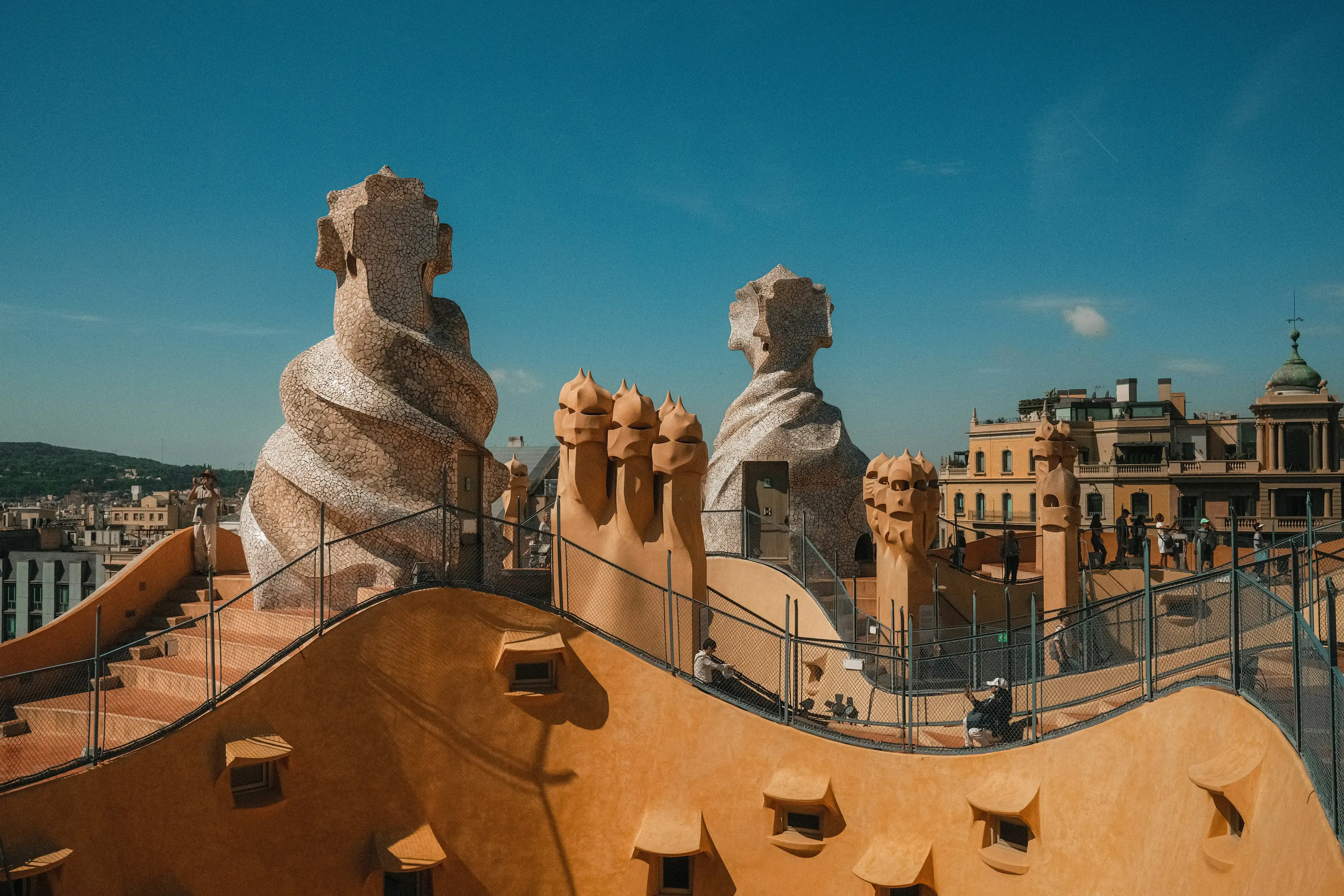 Gaudi's sculptural rooftop chimneys at Casa Mila in Barcelona, Spain, under a clear blue sky